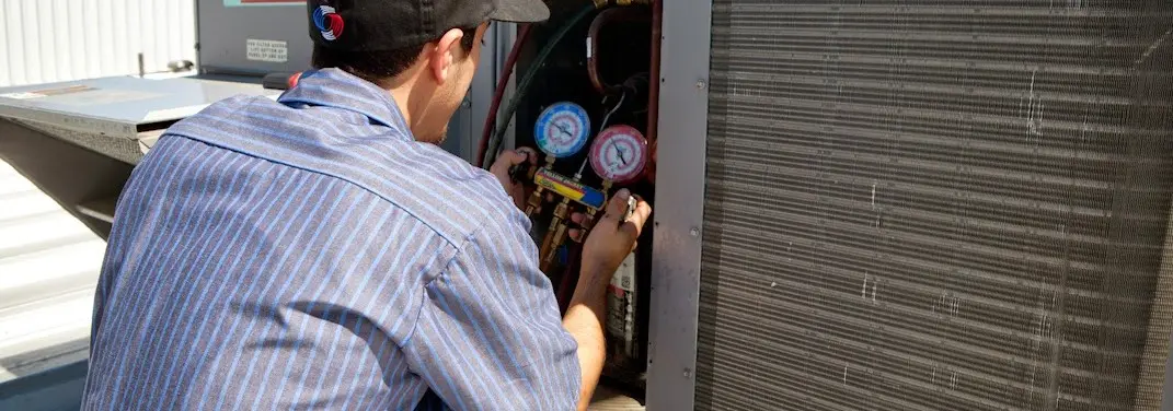 HVAC technician servicing a condenser unit in Sturtevant