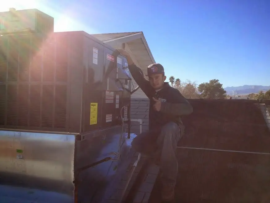 HVAC technician performing Heat Pump Repair on a rooftop unit in Sturtevant